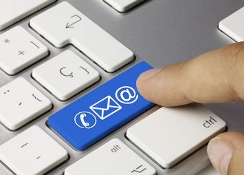 Das Bild zeigt eine Tastatur mit einer blauen Taste, auf der ein Briefumschlag zu sehen ist.